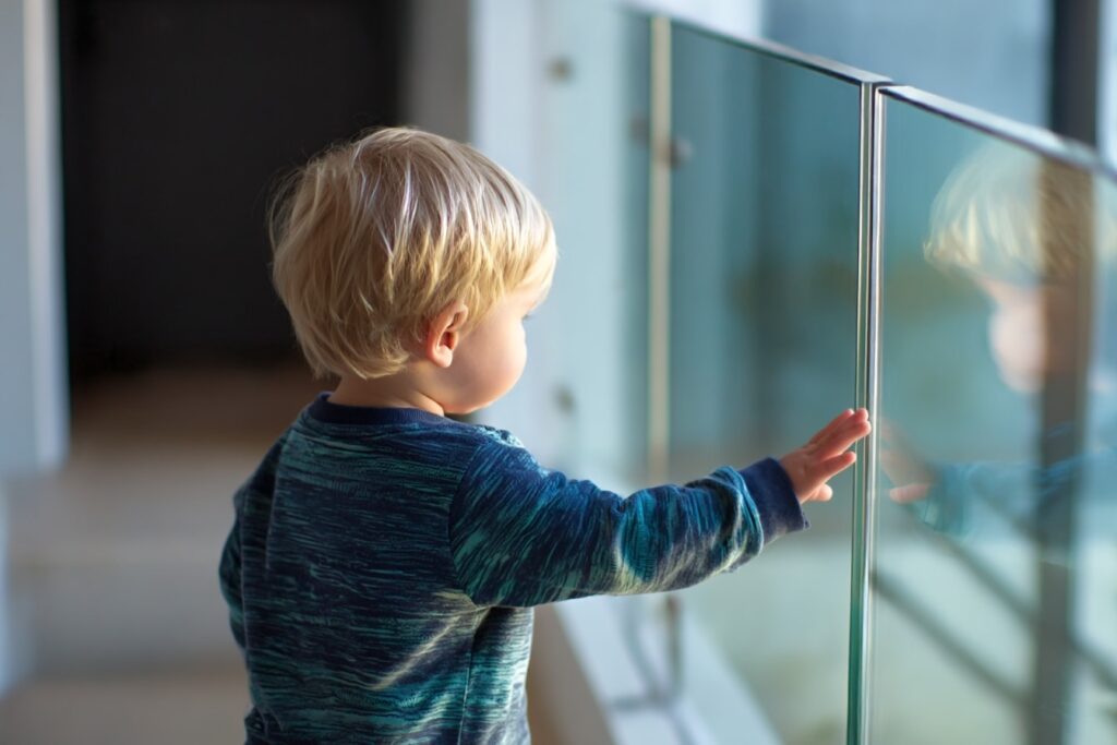 toddler exploring beside glass railing