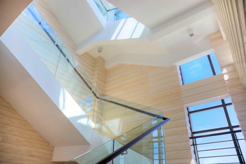 Indoor glass stair railing keeping sightlines open and allowing daylight to travel through an open-concept home
