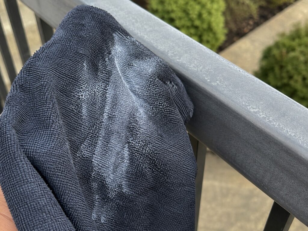 Dark cloth showing a chalky white residue after being wiped along a faded powder coated aluminum railing