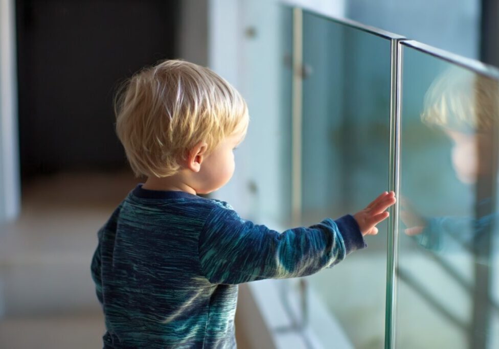 toddler exploring beside glass railing